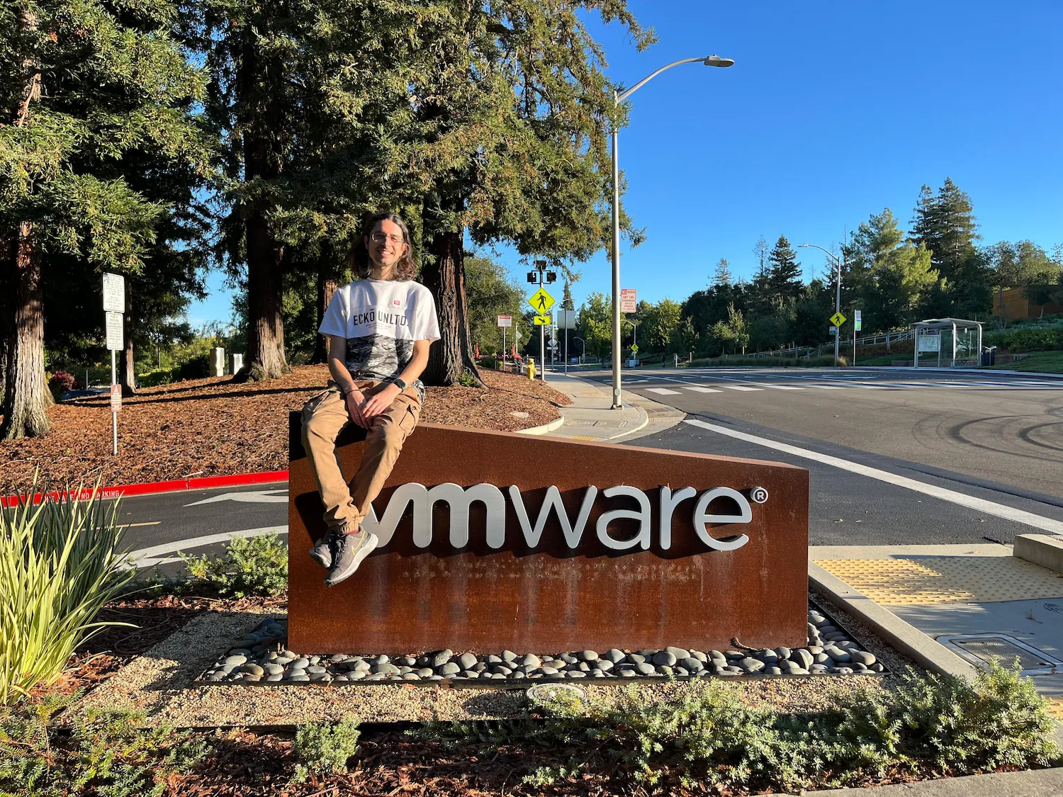 Yo en las oficias de VMware / Broadcom en Palo Alto. Estoy sentado encima de la señal de VMware en la entrada del campus