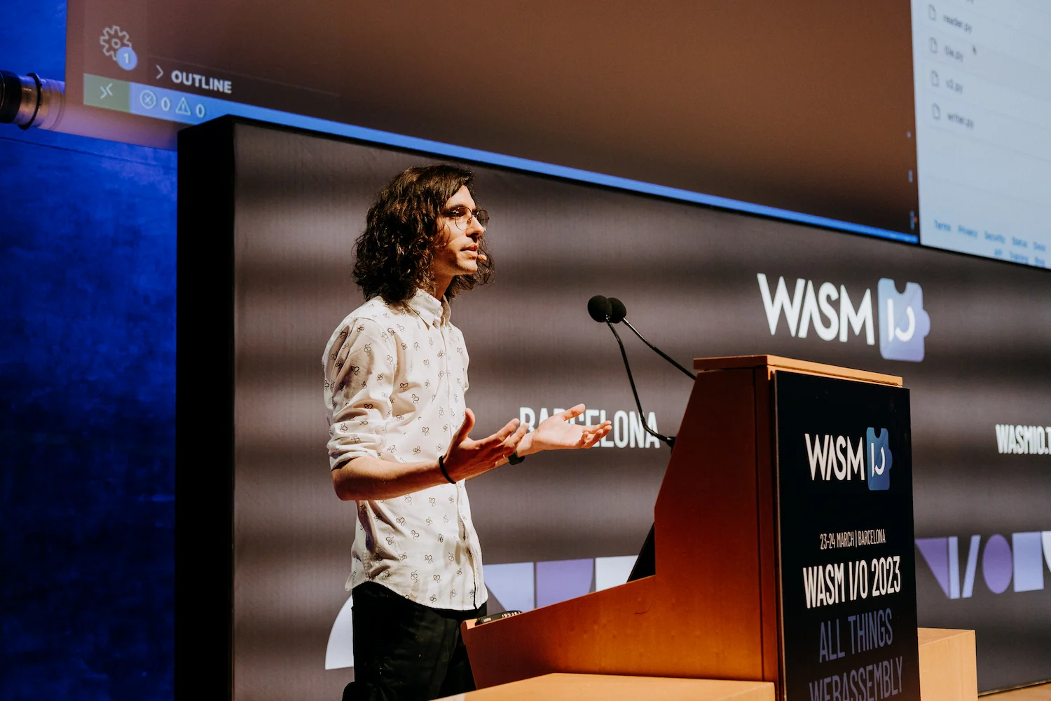 Yo hablando sobre el proyecto de Wasm Workers Server en Wasm IO. Llevo puesto una camisa blanca y tengo detrás mía el programa Visual Studio Code en la pantalla